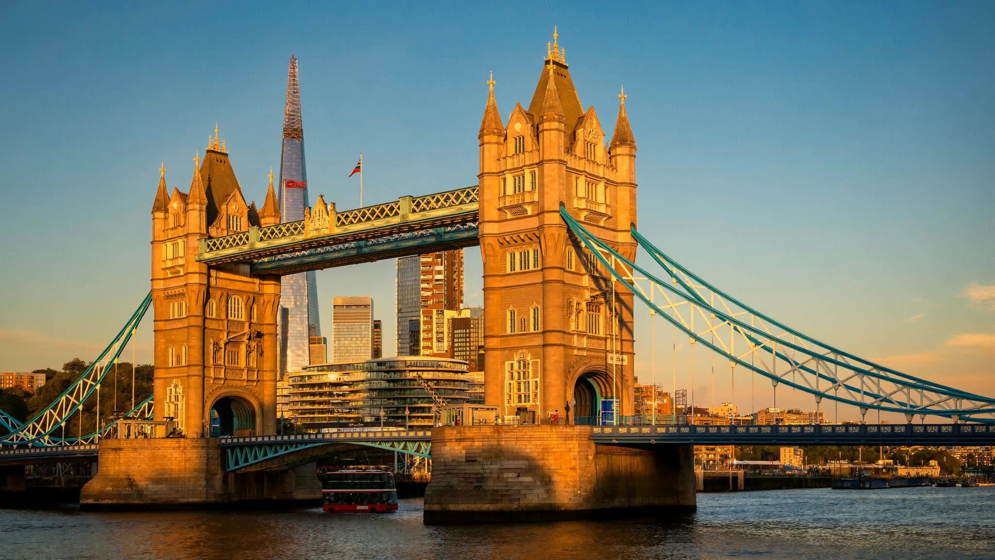 Tower Bridge and the River Thames at golden hour, a red London bus crossing